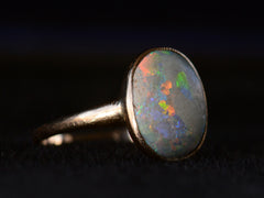 thumbnail of Left angled view of c1920 oval opal ring in rosy 10K gold, shown on black background.