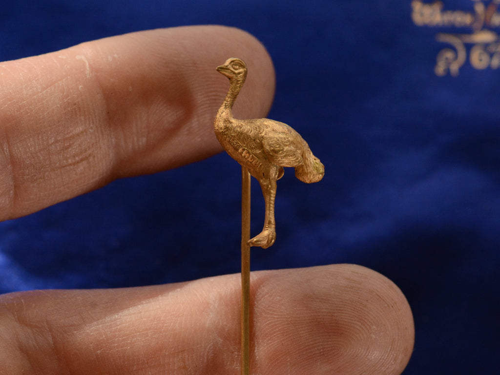 Antique yellow gold ostrich stick pin (in hand for scale) A mark stamped "14ct 585" is visible.