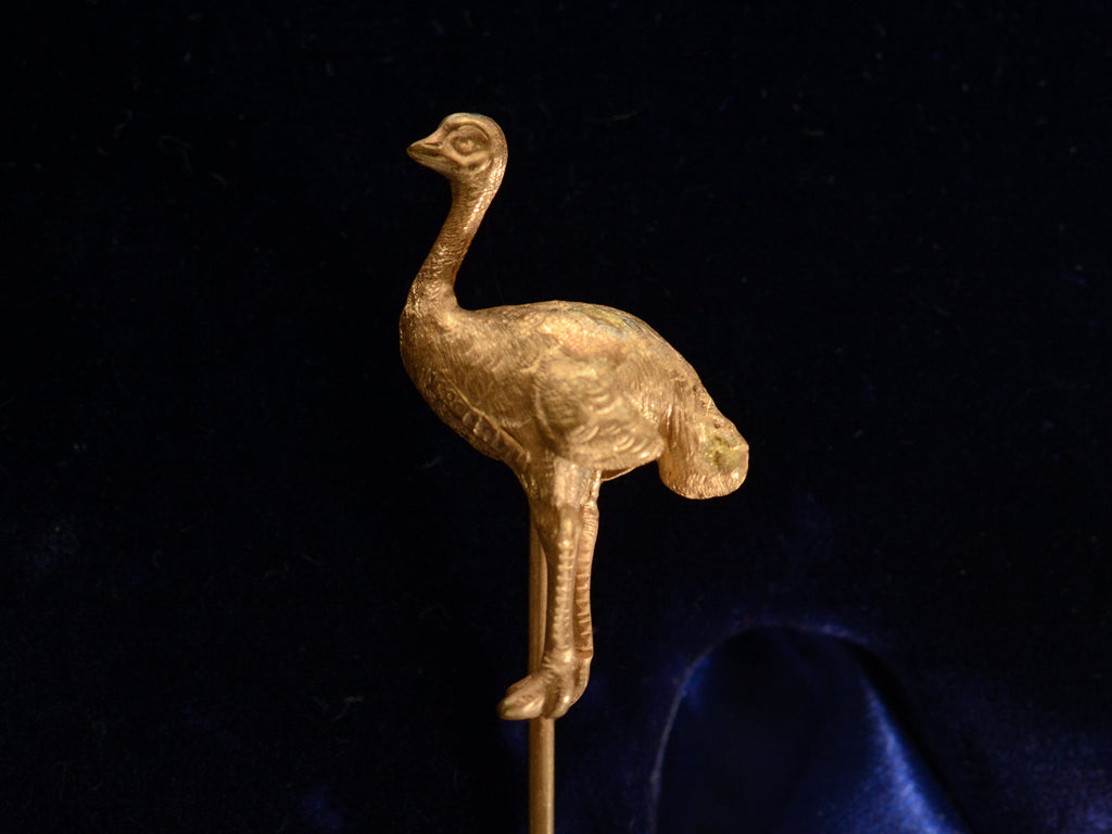 Side view of Antique yellow gold ostrich stick pin (on black background) A mark stamped "14ct 585" is visible.