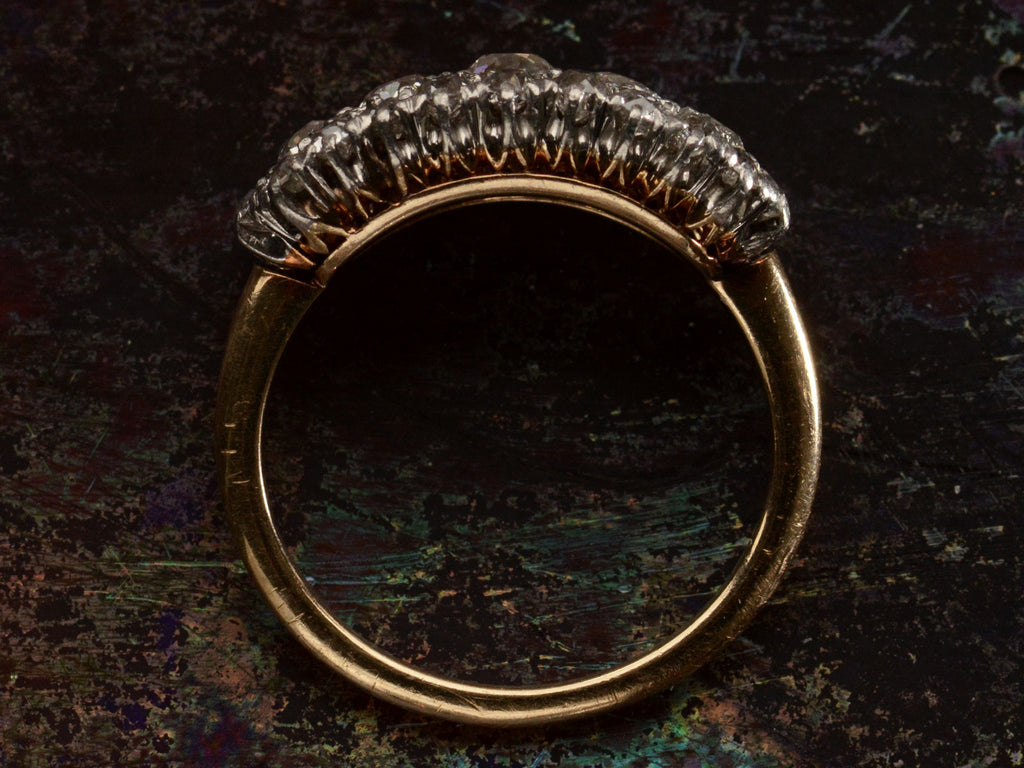 Side profile view of antique c1900 ring with an oval cluster of round old European cut diamonds set in platinum-topped 14K yellow gold, shown on dark background.