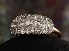 thumbnail of Right angled view of antique c1900 ring with an oval cluster of round old European cut diamonds set in platinum-topped 14K yellow gold, shown on dark background.