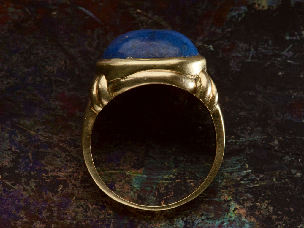 Side profile view of vintage c1980 ring with an oval blue lapis lazuli set in 18K yellow gold, shown on dark background.