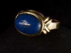 thumbnail of Angled view of vintage c1980 ring with an oval blue lapis lazuli set in 18K yellow gold, shown on dark background.