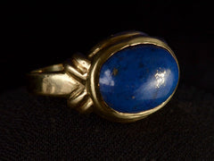thumbnail of Opposite angled view of vintage c1980 ring with an oval blue lapis lazuli set in 18K yellow gold, shown on dark background.