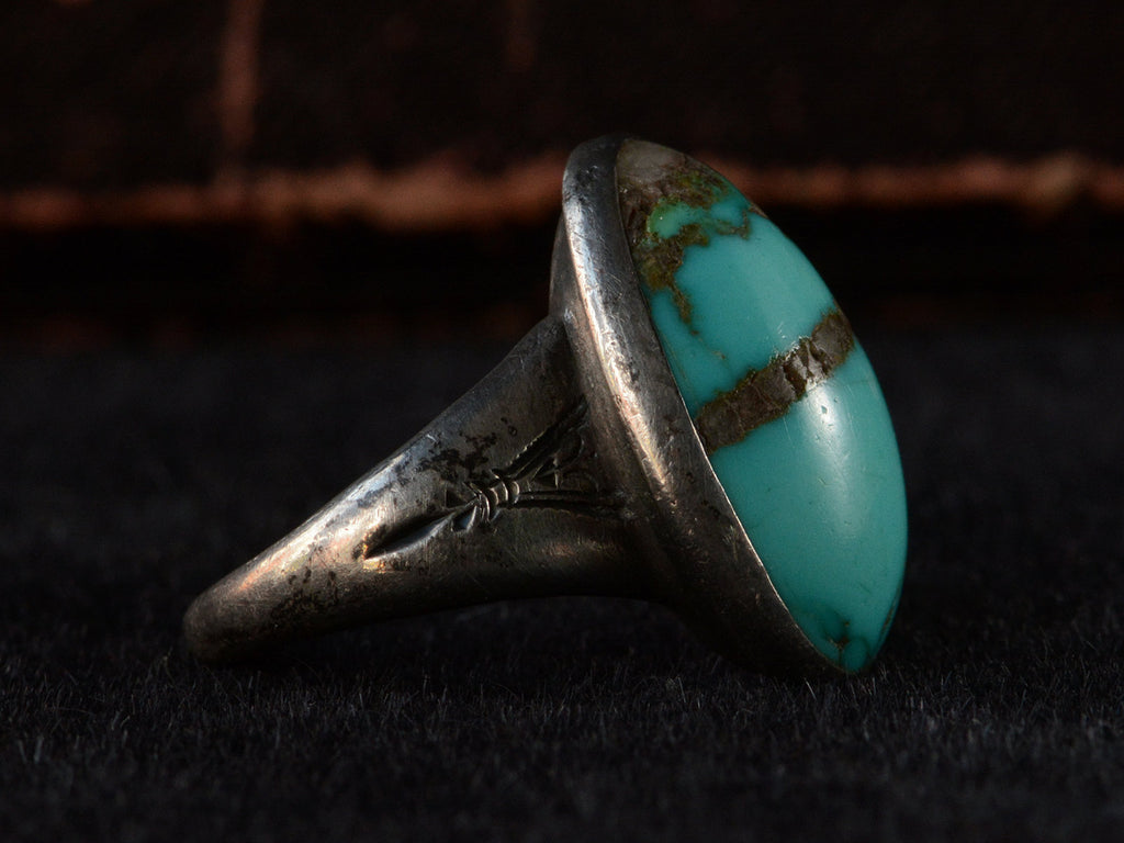 Left side view of c1950 Navajo Turquoise Ring in silver on black background.