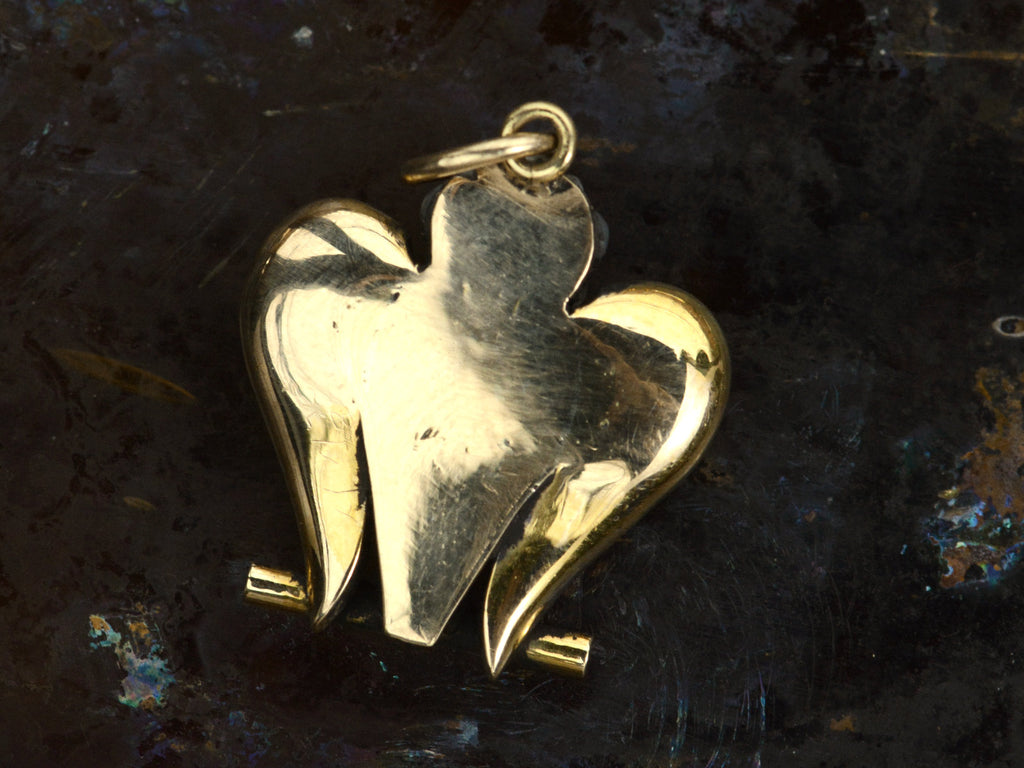 Back view of antique c1890 owl pendant shown on dark background.