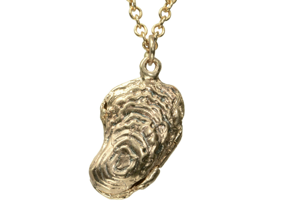 Detail of oyster shaped gold pendant locket, shown on white background.