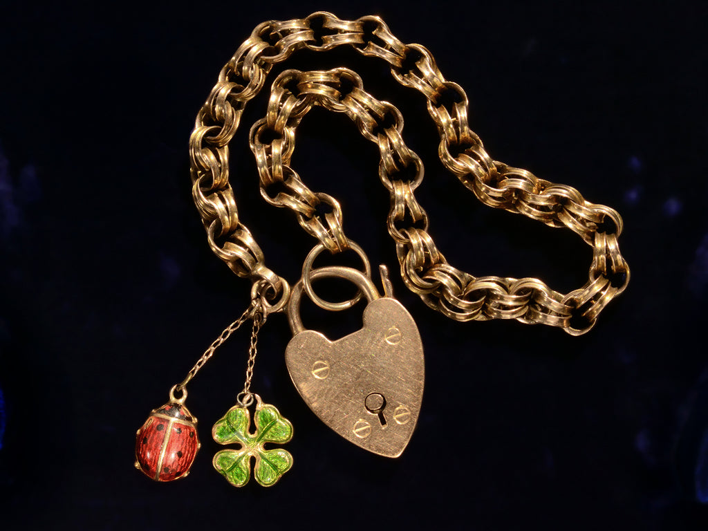 1904 Gold Padlock Bracelet with Ladybug and Clover Charms (detail shown on black background)