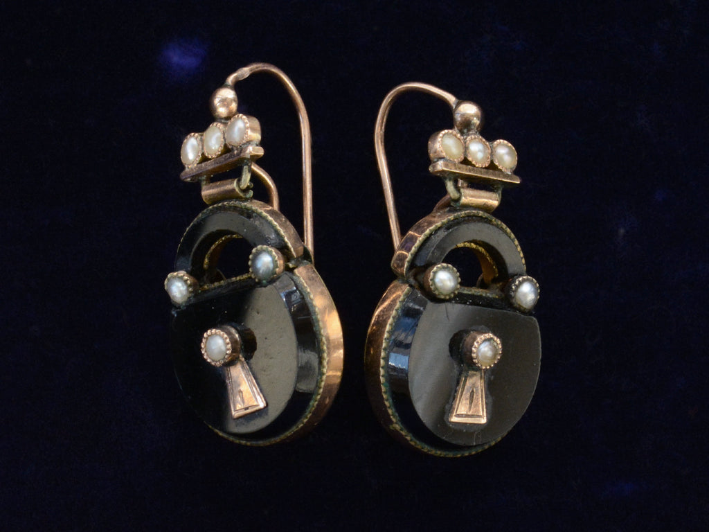 Angled view of c1880 Black Onyx and Pearl Padlock Earrings , shown on black background