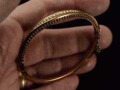 thumbnail of Side view of a narrow gold Victorian Pearl Bracelet with intricate Etruscan Revival granulation detailing, shown held in hand.