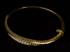 thumbnail of Elevated view of a narrow gold Victorian Pearl Bracelet with intricate Etruscan Revival granulation detailing, shown on dark background.