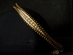 thumbnail of Front profile  of a narrow gold Victorian Pearl Bracelet with intricate Etruscan Revival granulation detailing shown on dark background.