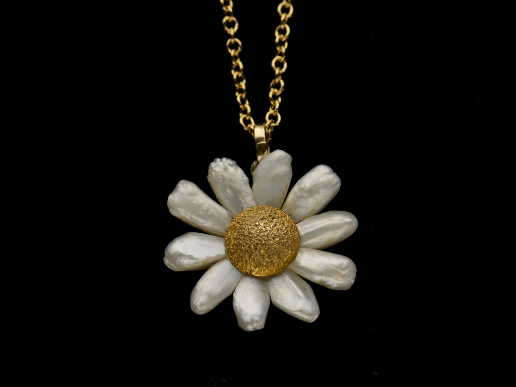 An antique daisy pendant with textured gold and pearl petals, shown on dark background.