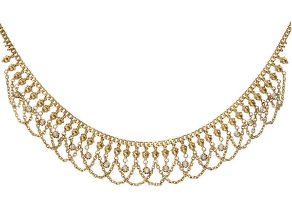 Detail view of a c1900 Edwardian chain collar with tiny seed pearl pendants and chain swags. Built in 14K yellow gold. Shown on white background.