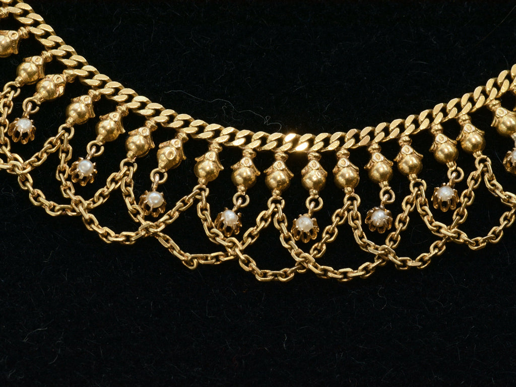 Close up view of a yellow gold c1900 Edwardian chain collar with tiny seed pearl pendants and chain swags shown dark background.