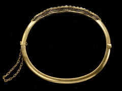 thumbnail of Side profile view of thin gold c1900 Art Nouveau bracelet with a wavy line of pearls. Shown on dark background.