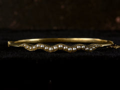 thumbnail of Front profile view of thin gold c1900 Art Nouveau bracelet with a wavy line of pearls. Shown on dark background.