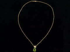 thumbnail of Pear-shaped peridot pendant set beneath three diamonds set in 18k yellow gold hanging on gold rope chain, shown on black background.