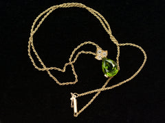 thumbnail of Detail chain and pear-shaped peridot set beneath three diamonds set in 18k yellow gold, shown on black background.