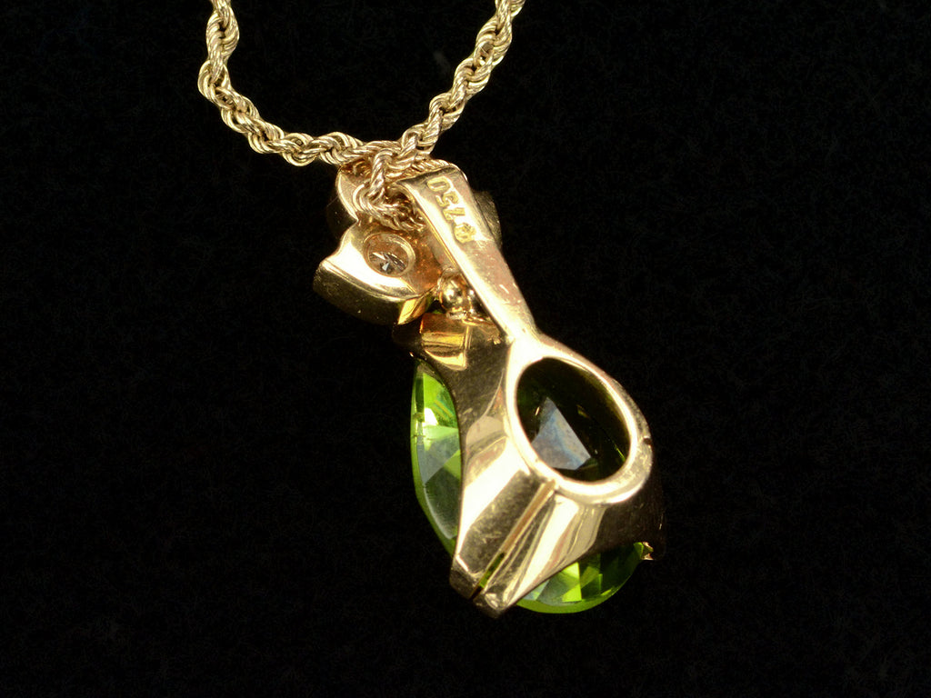 Reverse side detail of pear-shaped peridot set beneath three diamonds set in 18k yellow gold, shown on black background. A "750" stamp is visible.
