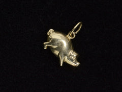 thumbnail of Gold pig charm on a black background, facing right