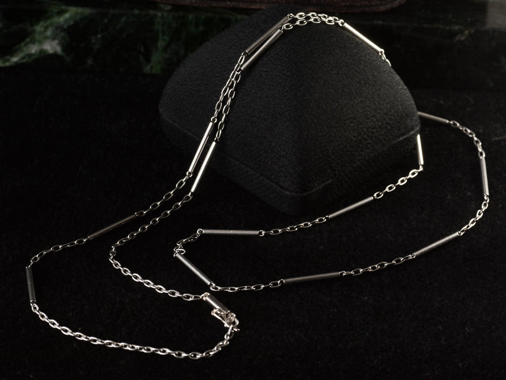 Art Deco platinum chain with cable and bar links, shown draped over black jewelry box.