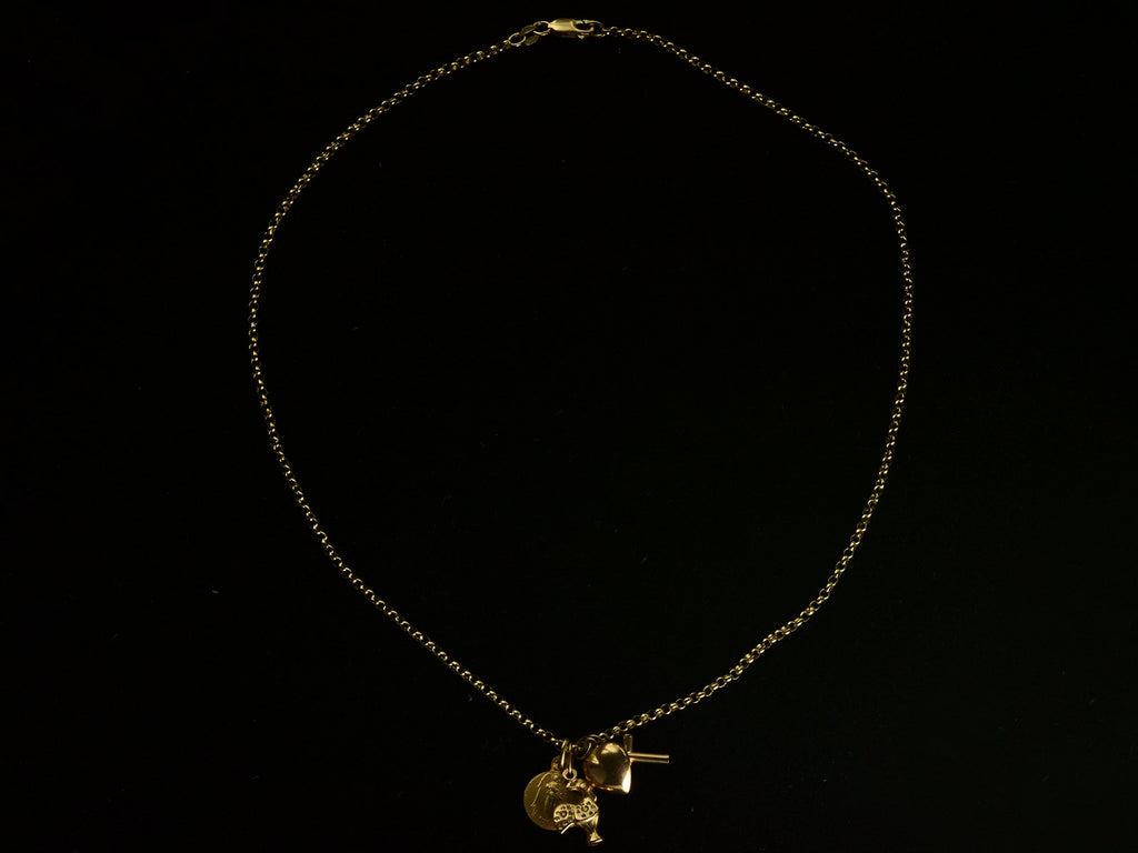 Vintage 19k yellow gold Portuguese charm necklace with four charms: a devotional medallion of Christ, a rooster, a heart, and a cross. Shown on black background. 