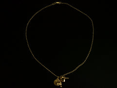thumbnail of Vintage 19k yellow gold Portuguese charm necklace with four charms: a devotional medallion of Christ, a rooster, a heart, and a cross. Shown on black background. 