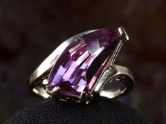 thumbnail of Front view of white gold ring with wing shaped faceted purple stone, on dark background.