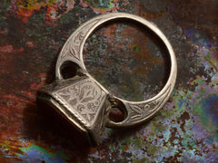 thumbnail of Angled side profile view of silver 19th century Persian carnelian intaglio ring.  (shown on colorful background)