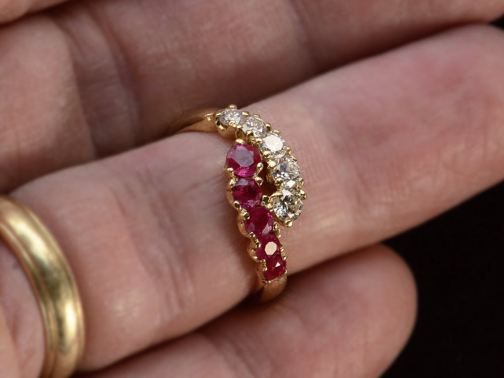 c1970 Yellow Gold Ring with rows of pink rubies and white diamonds curling around each other. On finger.