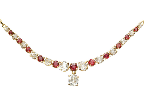 Close up on a vintage yellow gold necklace with alternating red rubies and old mine cut diamonds, shown on white background.