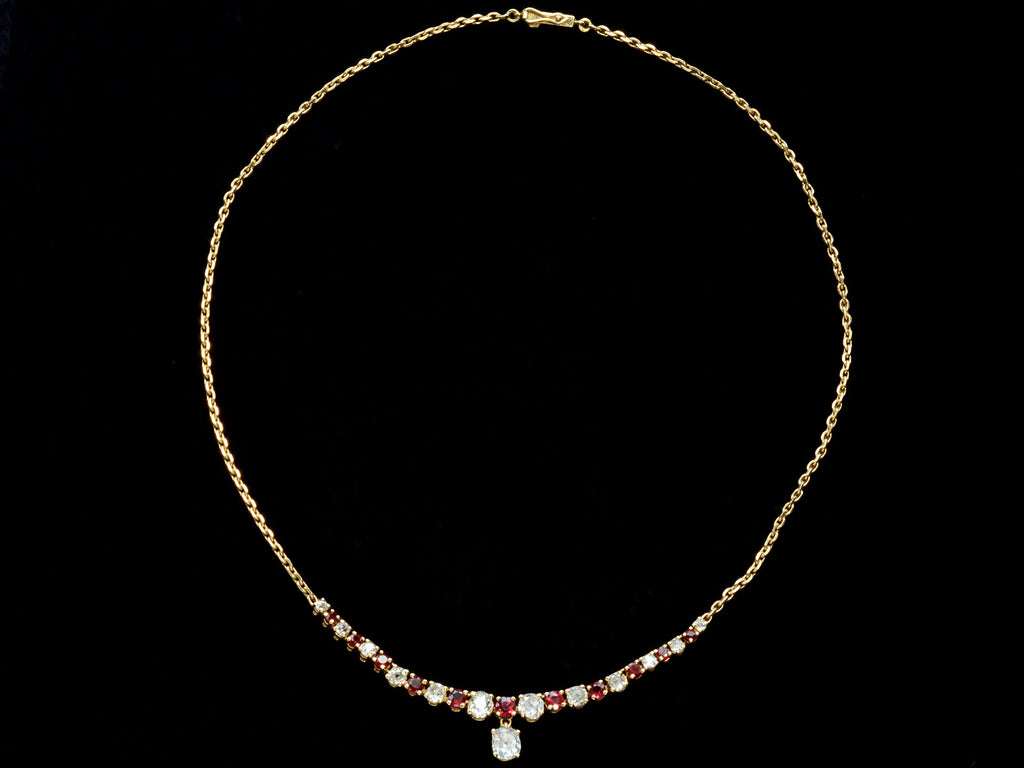 A vintage yellow gold necklace with alternating red rubies and old mine cut diamonds, shown on black background.