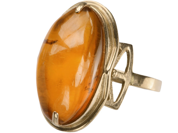 A vintage ring with an oval amber cabochon in 14k rose gold, shown on white background.