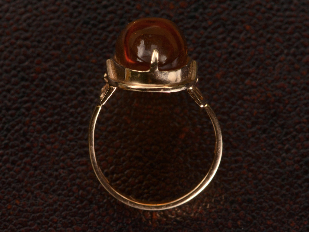 Side profile view of vintage ring with an oval amber cabochon in 14k rose gold, shown on dark textured background.
