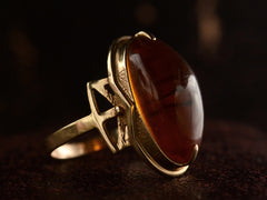 thumbnail of Angled side view vintage ring with an oval amber cabochon in 14k rose gold, shown on dark background.