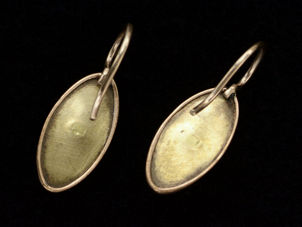 Reverse side of gold earrings with marquise shaped iridescent pale blue saphiret cabochons, shown on black background.