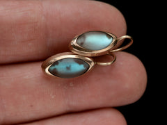 thumbnail of Second pair of gold earrings with marquise shaped iridescent pale blue saphiret cabochons, shown on fingers.