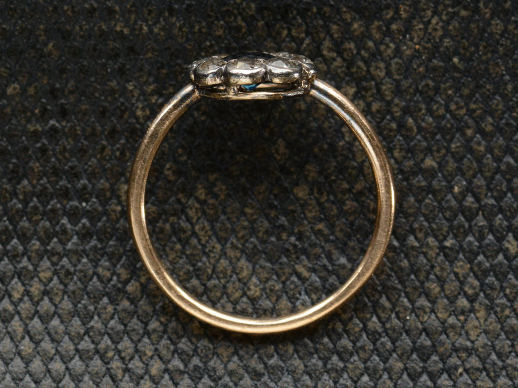 Side profile of antique silver topped gold ring with blue and white sapphires (shown on dark background)