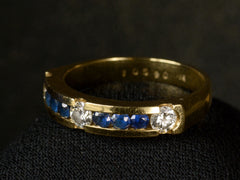 thumbnail of Elevated angled view of a vintage yellow gold ring with three diamonds interspersed with blue sapphires. Shown on white background. Faint markings inside the ring read "10590 18K"