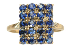 thumbnail of A vintage yellow gold ring with a rectangular cluster of blue sapphires, shown on white background.