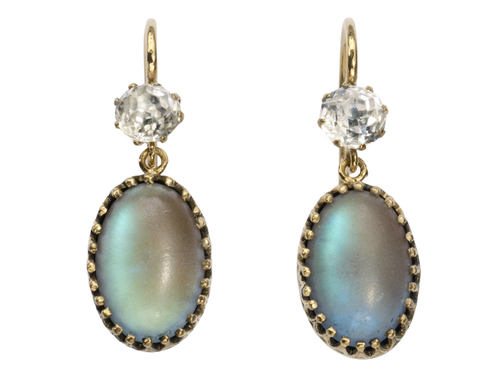 Pair of earrings with white crystal tops and oval pendants of pale blue glass with a reddish glow. Shown on white background.