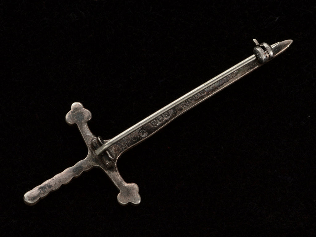 Revese side of  Scottish silver sword pin, shown on black background. Scottish hallmarks are visible but not legible