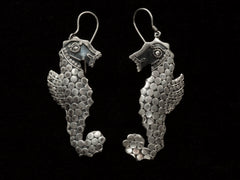 thumbnail of A pair of silver seahorse drop earrings textured with disks, shown against a plain black background.