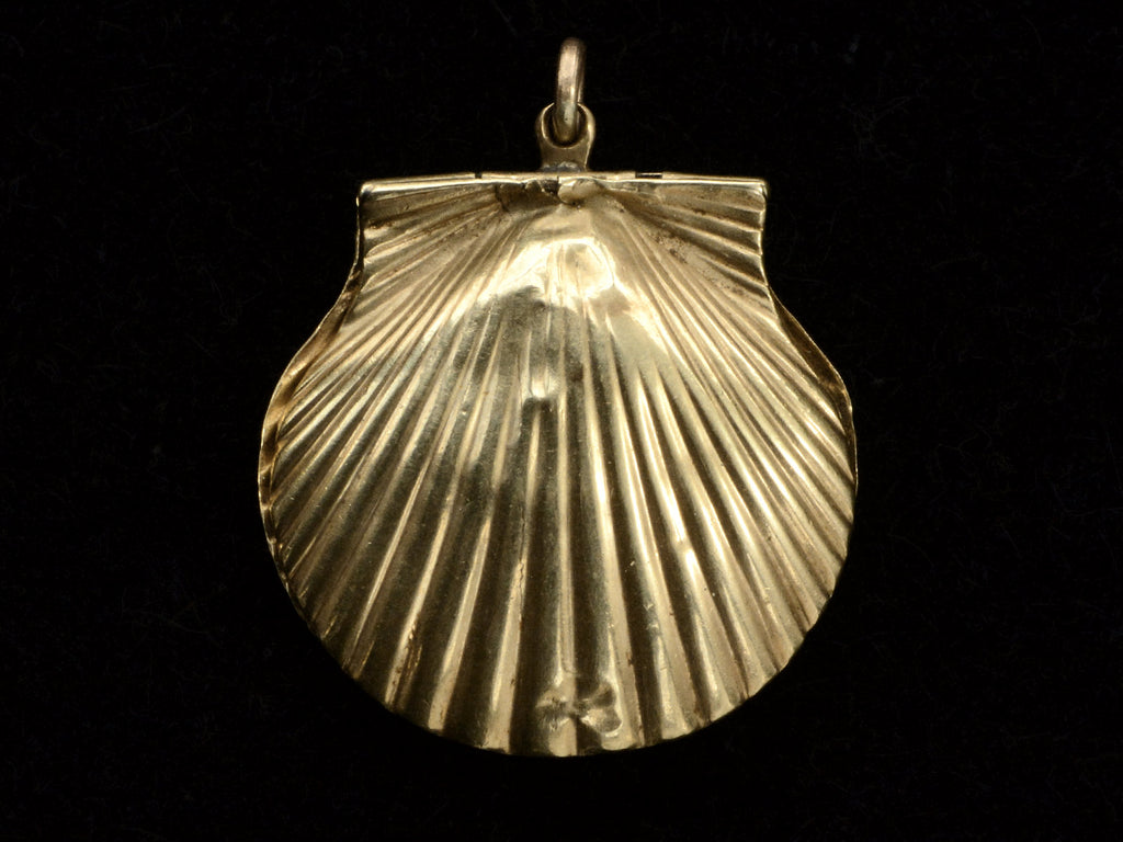 Reverse side of an antique Victorian scallop shell locket in gold, on black background