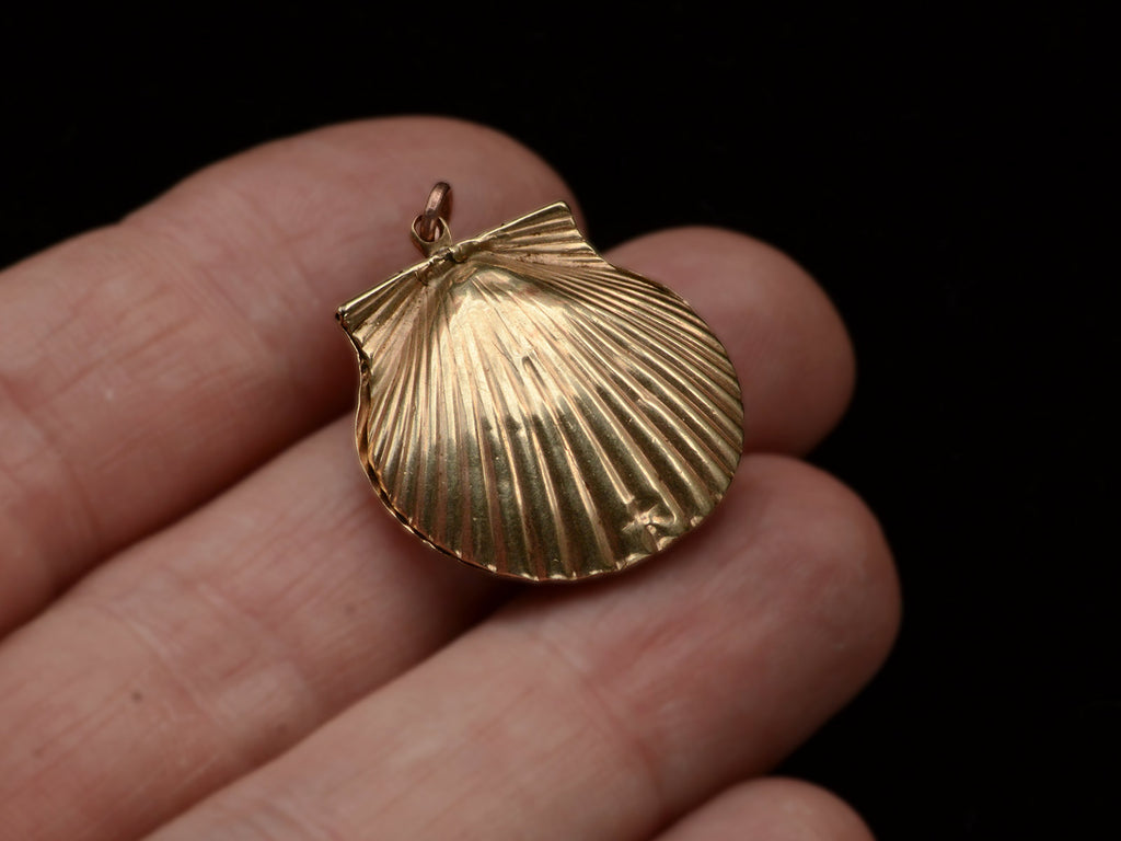 Reverse side of an antique Victorian scallop shell locket in gold, held on hand