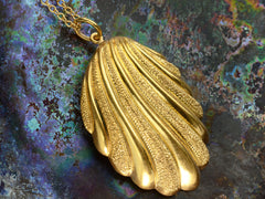 thumbnail of Angled detail view of Victorian shell pendant necklace with detailed gold work, shown on colorful textured background.