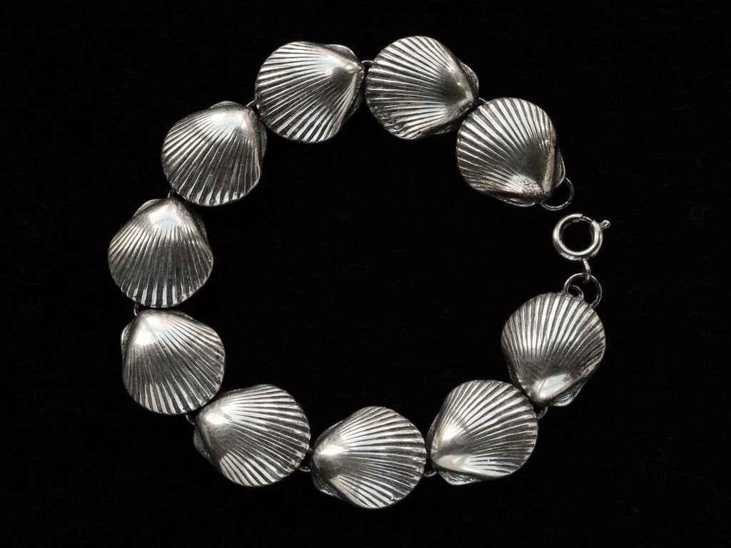 A silver bracelet with scallop shell links, on black background.