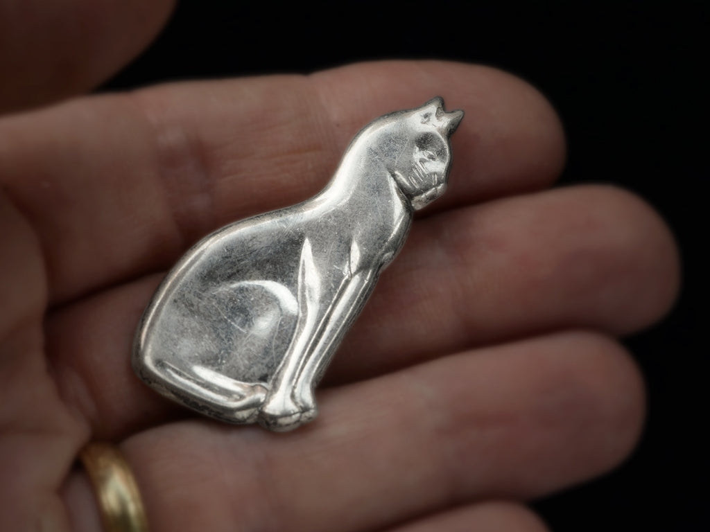 A vintage silver cat brooch shown held in hand