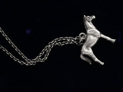 thumbnail of Opposite side of silver horse pendant on a chain against a black background